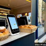 디지털화폐의 블록체인 기술 적용 사례 - Photorealistic Parisian neighborhood bakery checkout using digital euro payments, a customer holding...